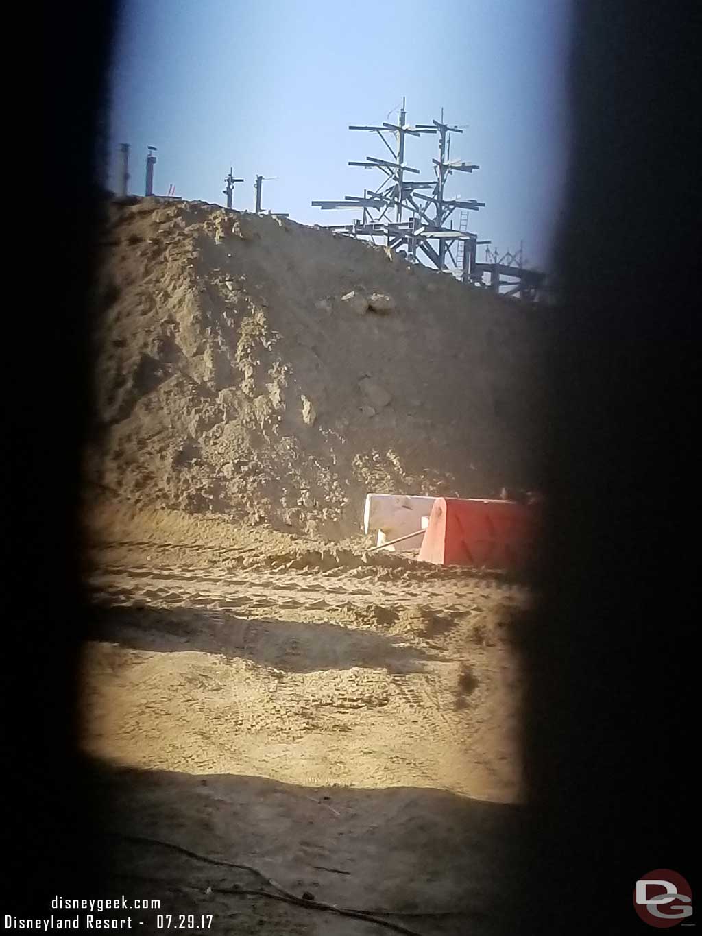 7.29.17 - A look through the fence here shows a pile of dirt obstructing our view.  Beyond it the steel structure for the rock work facade on the show buildings.