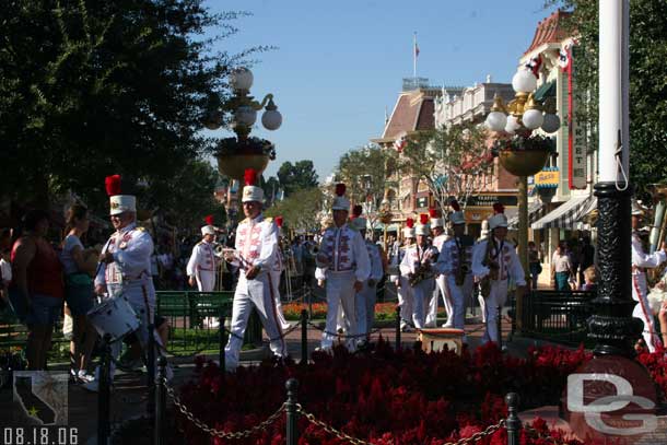 The Disneyland Band marches down the street, performs at the point of town square then circles the flagpole