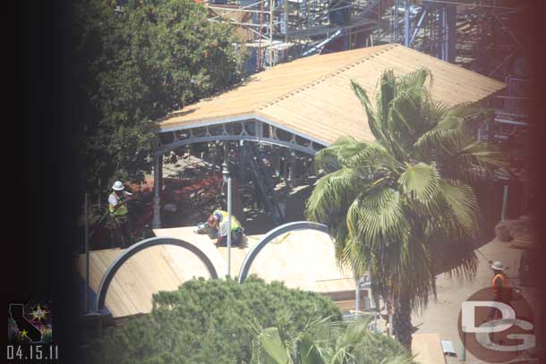 The roof looks to be on the shaded area and in the foreground they are working on the roof for the seating area that lines the parade route.