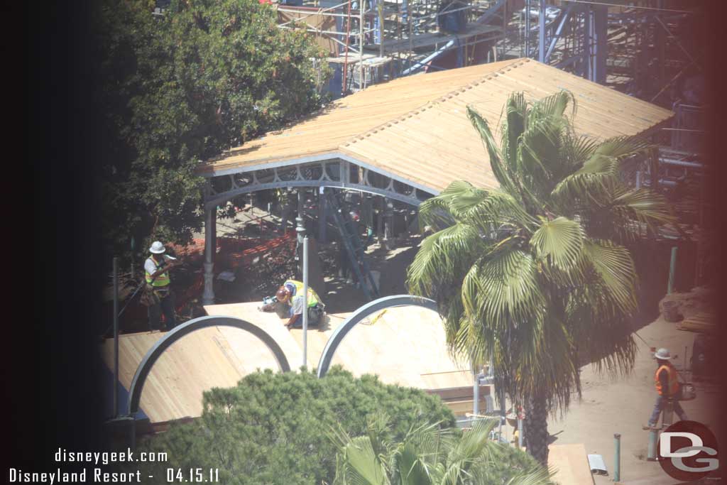 The roof looks to be on the shaded area and in the foreground they are working on the roof for the seating area that lines the parade route.