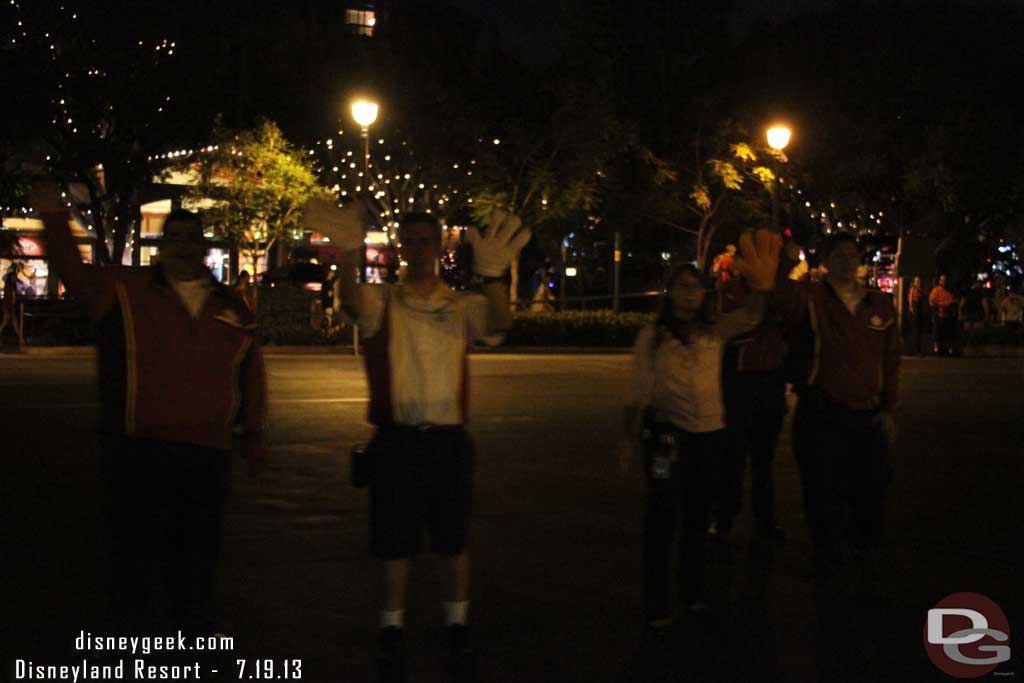 A group of cast members standing in the middle of the tram stop waving to trams.