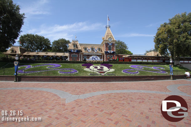 An unobstructed daytime picture of the Main Street Train Station, Floral Mickey and 60th Anniversary signage as the Ward Kimball arrives.