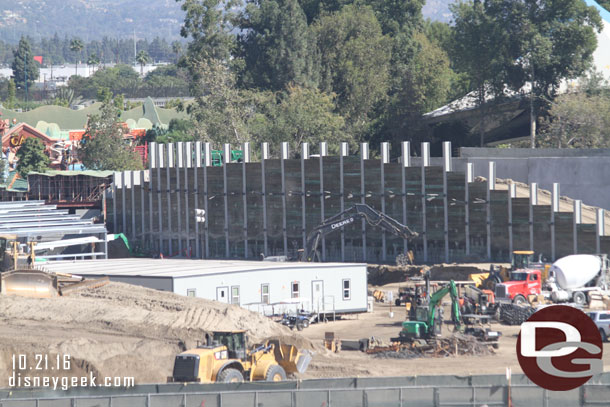 They continue to remove dirt from behind the retaining wall.