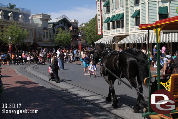 A cast member pushing a guest stroller so the guest and family can ride the street car.