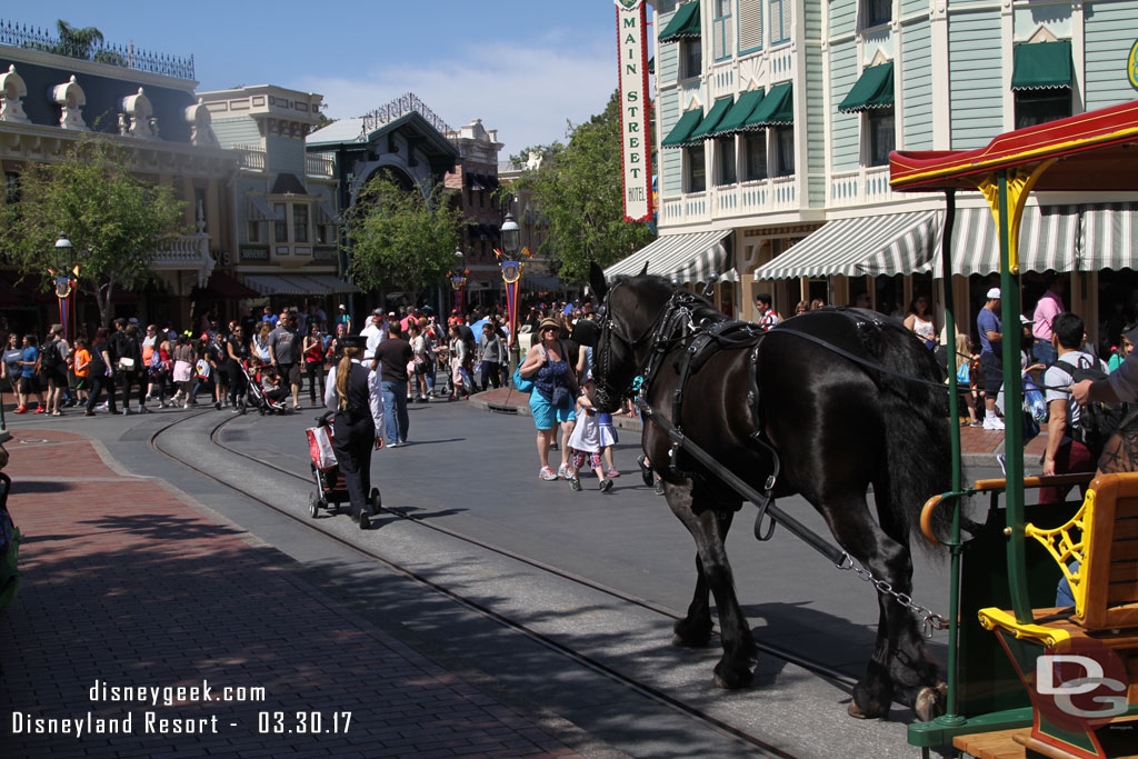 A cast member pushing a guest stroller so the guest and family can ride the street car.