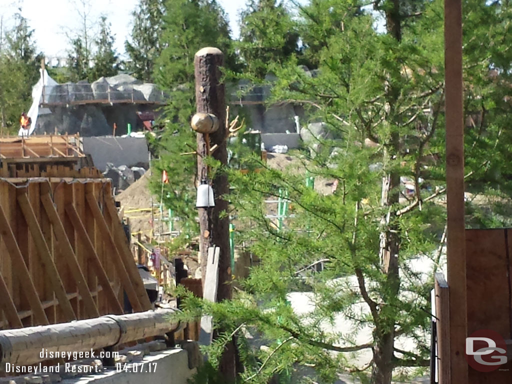 The the left a new tree and the back of the wall along the walkway.