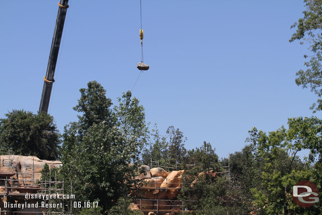 The crane we saw on the Star Wars side from the parking structure is lifting a large rock into place on this side of the berm.