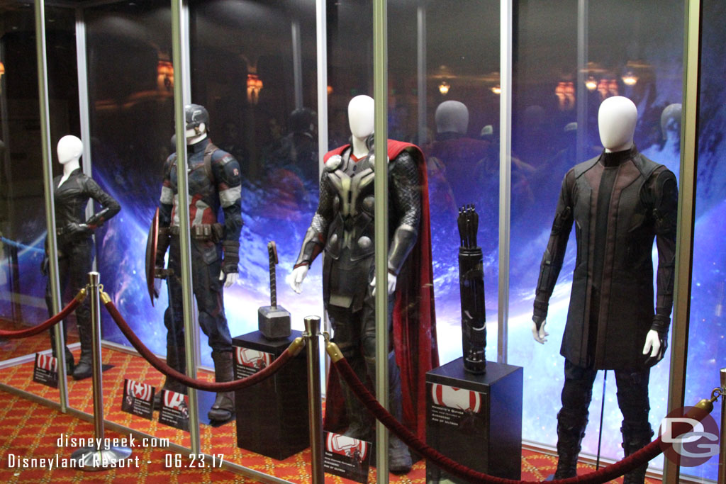 Four Avenger costumes and props in the pre-show waiting area.