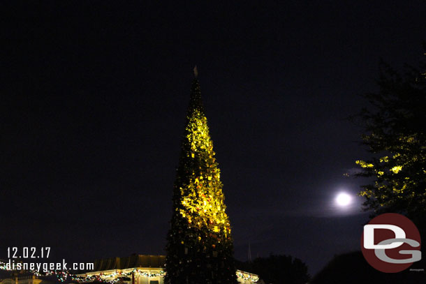 The Christmas tree with the nearly full moon rising and some spot lights hitting it.