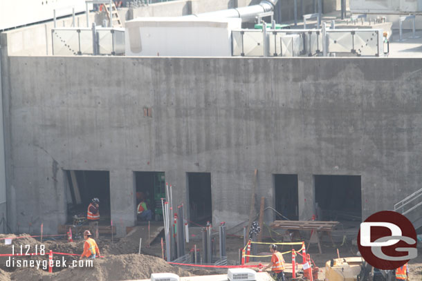 Conduit and utility work continue behind the concrete building.