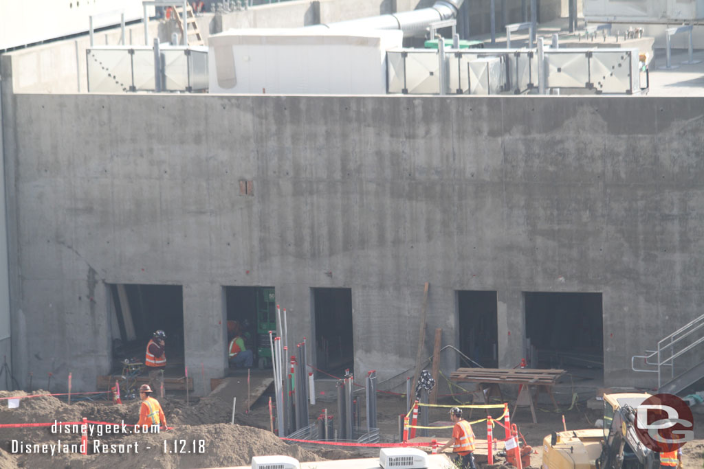 Conduit and utility work continue behind the concrete building.