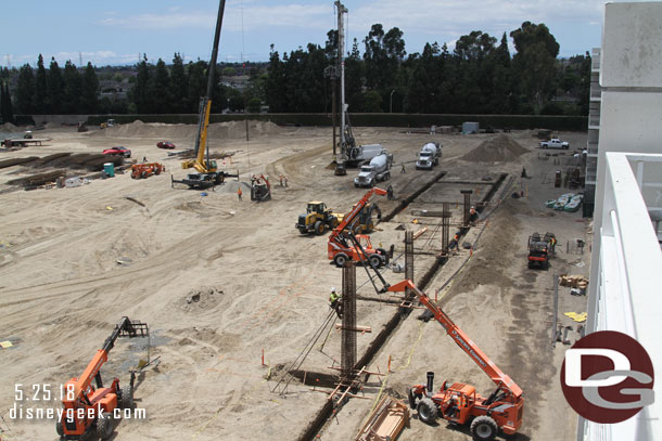 On the left you can see a drill and a crane working.  The process is they drill a deep hole and fill it with concrete.  They then lower a rebar column into it and sink it to ground level.  It is allowed to set/dry.  Then they come back and start assembling the above ground portion.