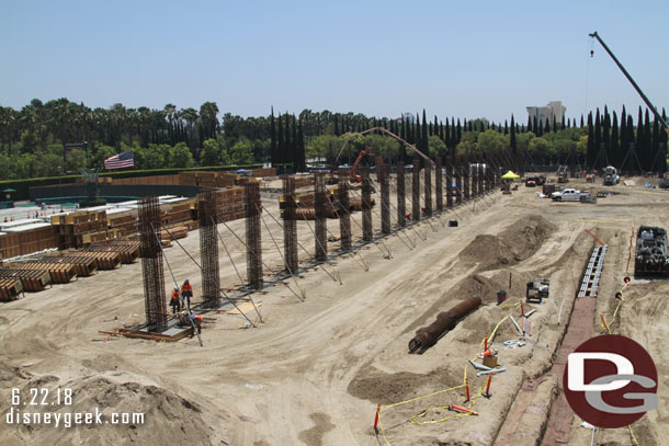 A row of columns parallel to the tram stop and conduit being laid/buried on the right.