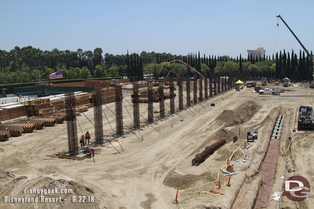 A row of columns parallel to the tram stop and conduit being laid/buried on the right.