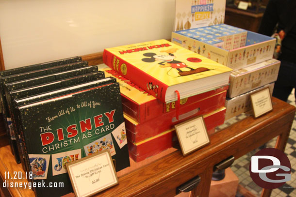 A  Christmas Card and large Mickey Mouse book for sale near the registers.