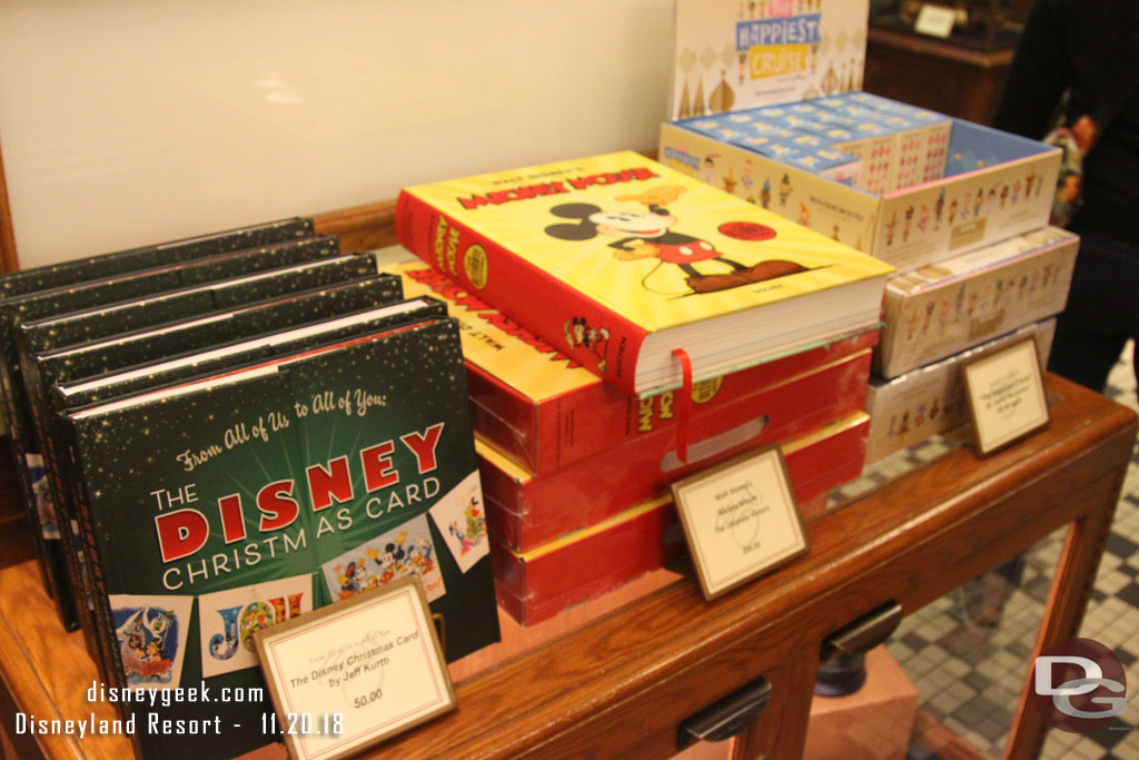 A  Christmas Card and large Mickey Mouse book for sale near the registers.