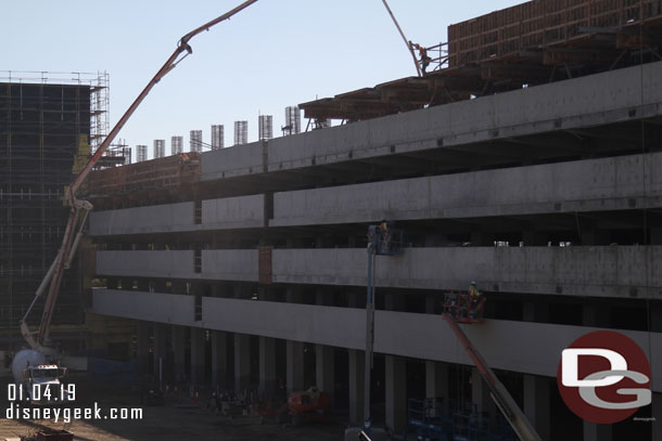 Panning to the right a concrete pumper sending concrete to a team working on supports on the 5th floor it appears.