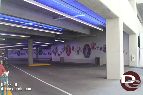 The far wall features bubbles with characters in them.  There are two driveways so trams can pass and in the far left is the Mickey Van load/unload area and some space for other Disney vehicles.