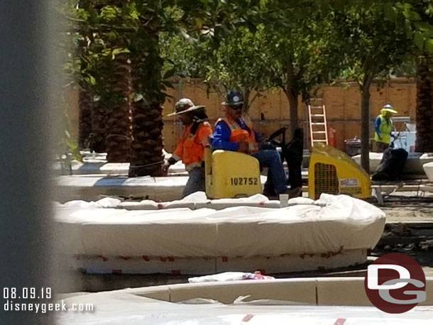 Crews in the middle are compacting and leveling the ground in preparation for pavers.  In the background they have started to install the pavers.