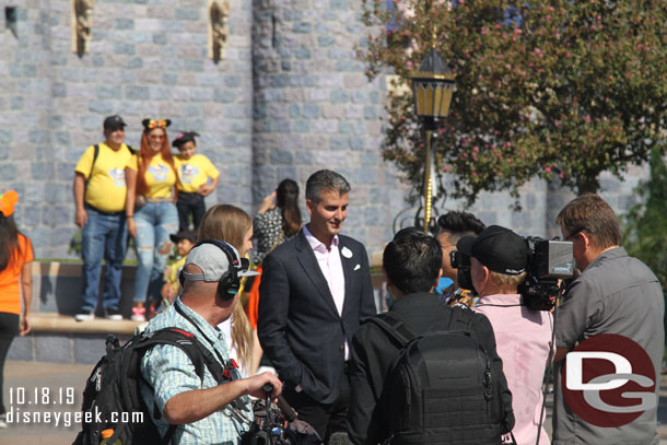 The outgoing president of the Disneyland Resort taping something in front of the castle.