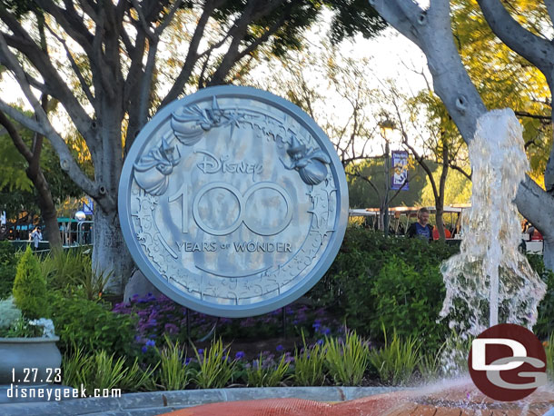 A Disney100 medallion near the fountain