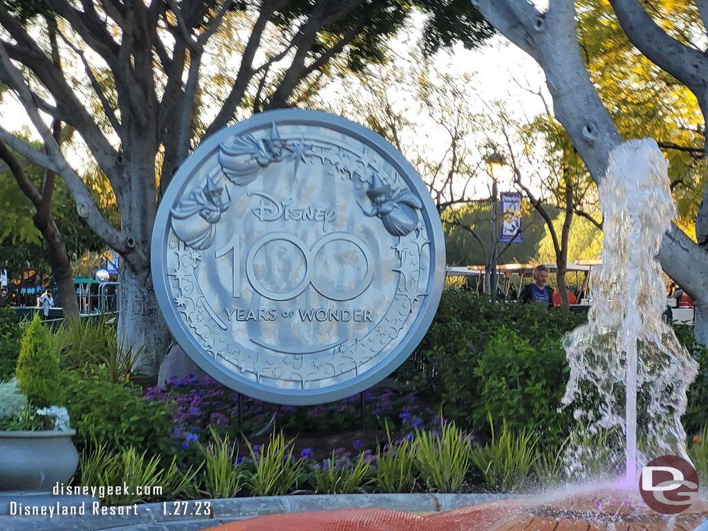 A Disney100 medallion near the fountain