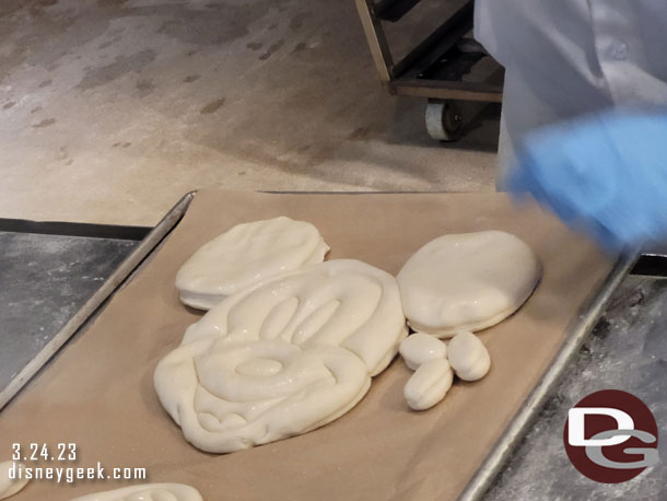 Then finally another cleans away the excess dough and assembles Mickey