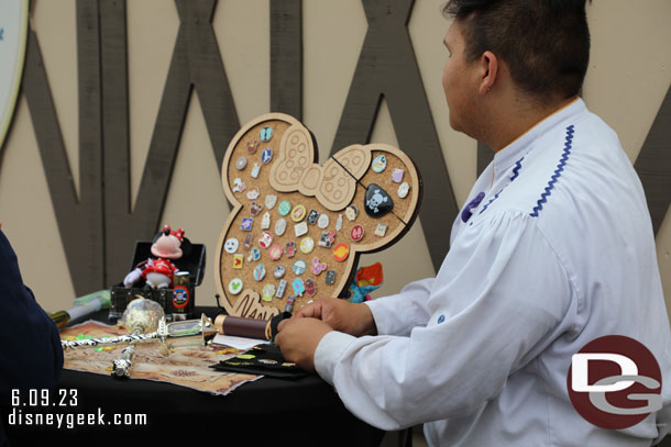 Pin trading and some props on a table in front of the construction wall.