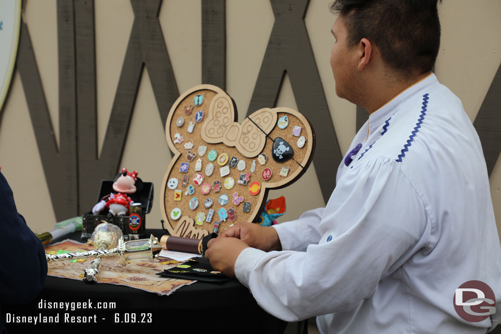 Pin trading and some props on a table in front of the construction wall.