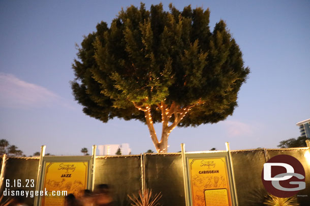 The tree beyond the construction wall has lights on still