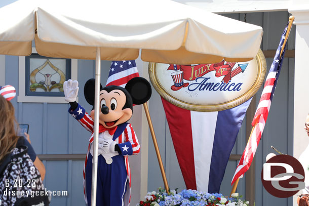 Mickey waving to Minnie as she walks by