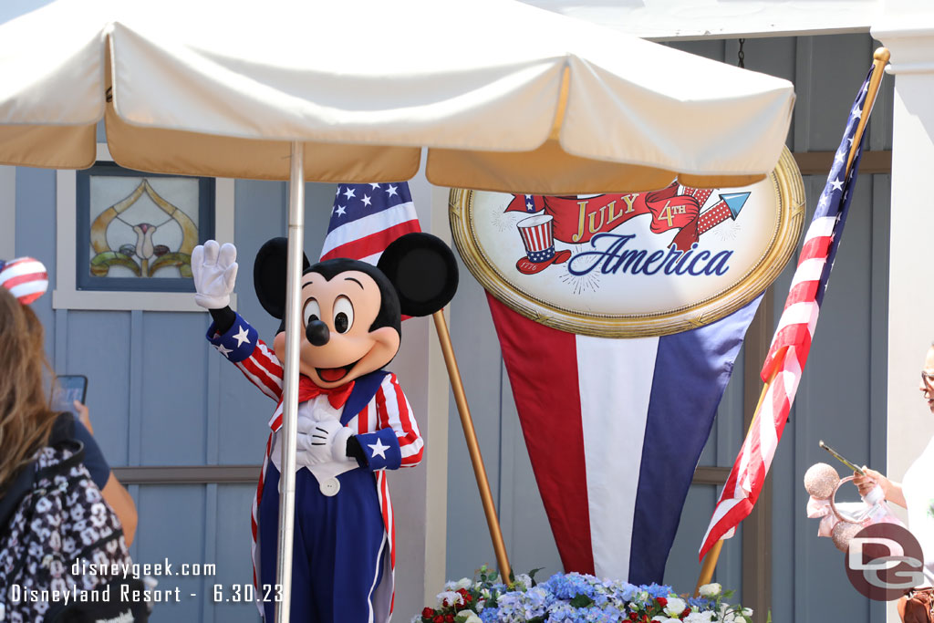 Mickey waving to Minnie as she walks by