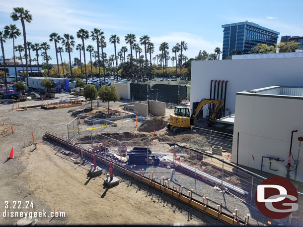 Trees are staged, and some installed in the area behind the buildings.