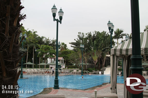 The outdoor pool area during the day.  One guest doing laps.