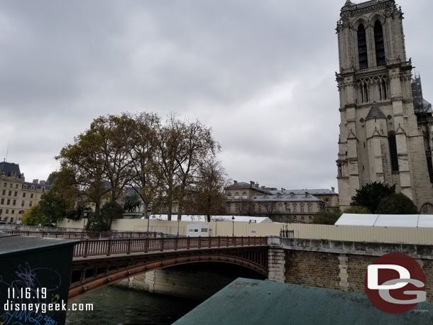 Construction walls/fences line the opposite bank around Notre Dame.