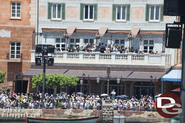 Guests crowded on balcony and opposite shore.