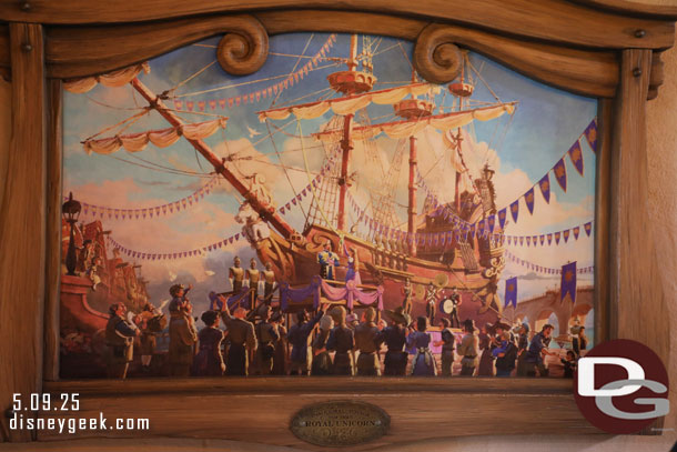12:01pm - The queue moves under cover and inside building with open walls on a two sides.  Artwork on the wall.