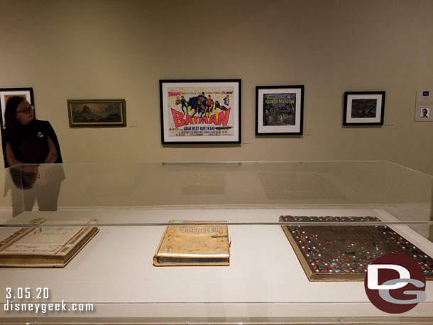 Thought this was an interesting framing.. the display case has books from classic Disney films. Behind it artwork including a Batman movie poster.