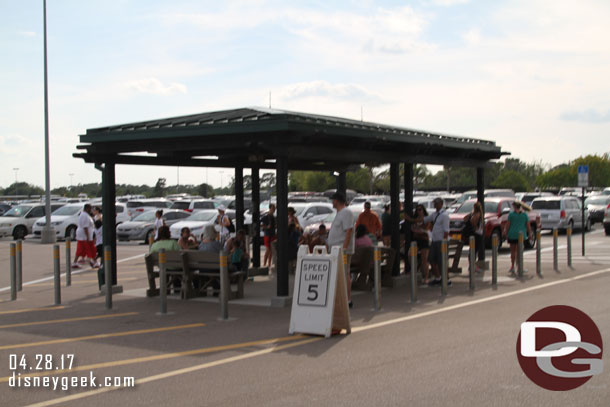 A good number of guests waiting for a bus in the parking lot.