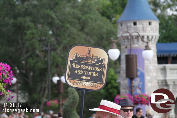In the hub a cast member with a sign directing guests looking for tours and dining checkin this morning.