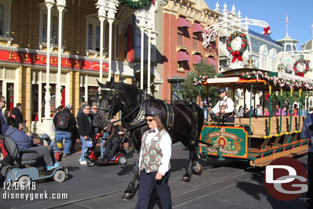 A horse drawn trolley making its way along Main Street USA decked out for Christmas.