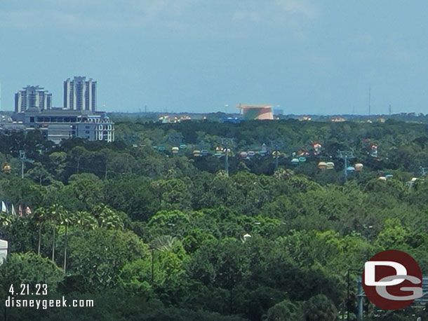 The Disney Skyliner in the foreground and Team Disney building rising above the tree line in the background.